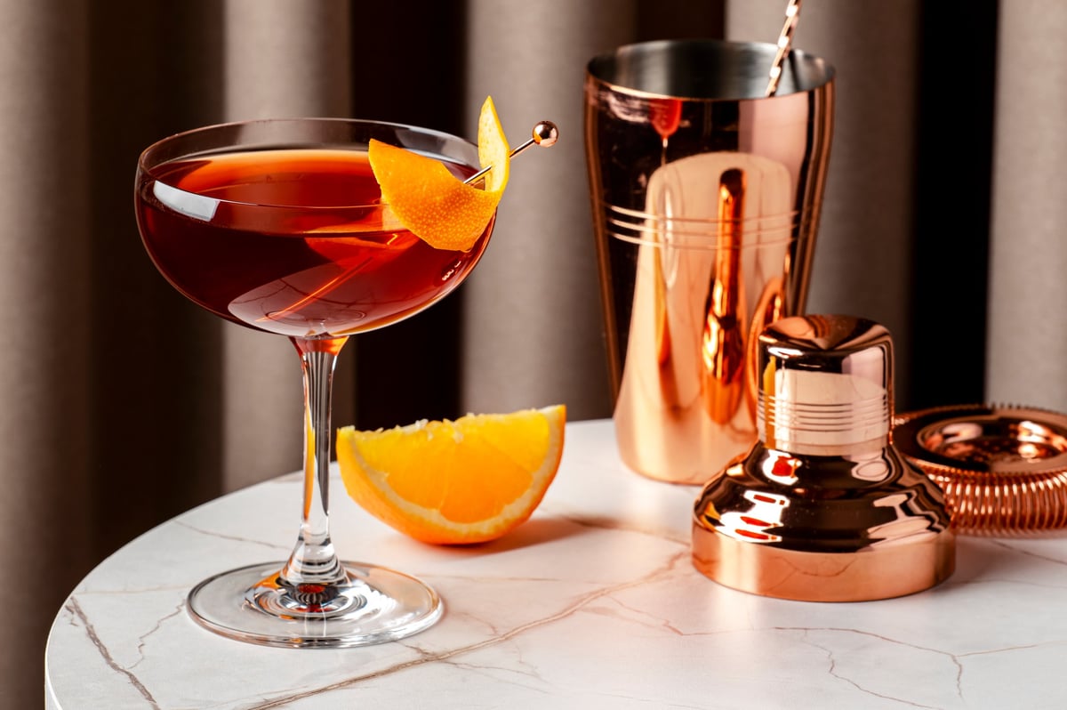A crafted cocktail garnished with orange peel on a stylish table setting